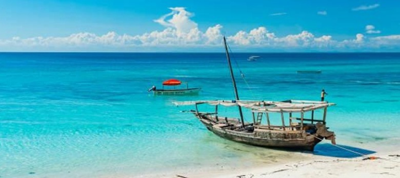 Pristine white sandy beach on Zanzibar Island,
         with turquoise waters and traditional dhows sailing in the background.